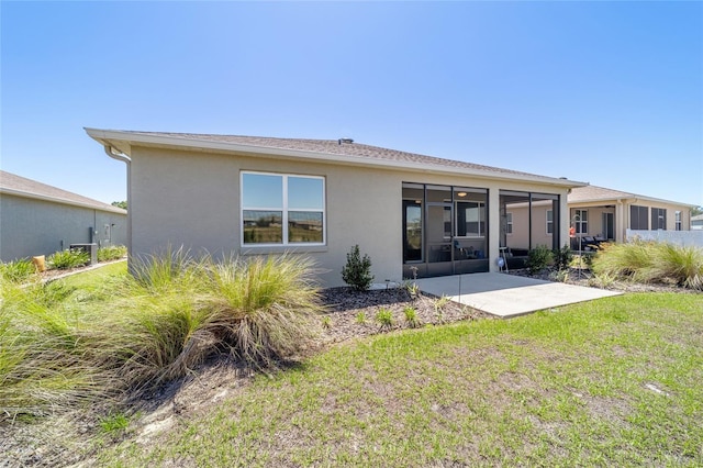 rear view of property with a patio, a sunroom, a yard, and stucco siding