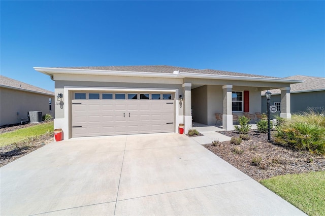 view of front facade featuring stucco siding, driveway, central AC, and a garage