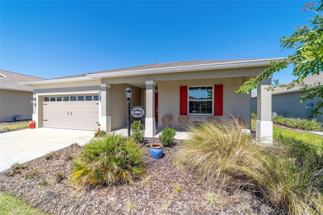 view of front of property with stucco siding, covered porch, a garage, and concrete driveway