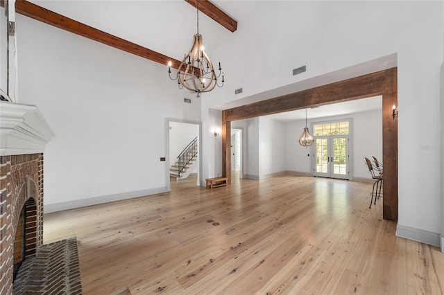 1251 SW 43rd Pl, Ocala, FL 34471 - unfurnished living room featuring a brick fireplace, a chandelier, stairs, beamed ceiling, and light wood finished floors