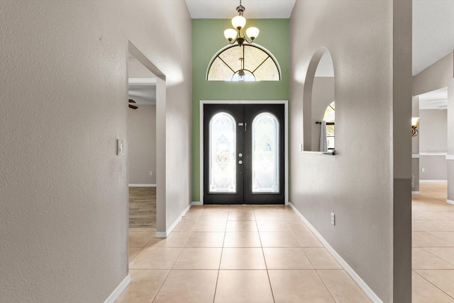 foyer entrance with french doors, tile patterned floors, baseboards, and a textured wall