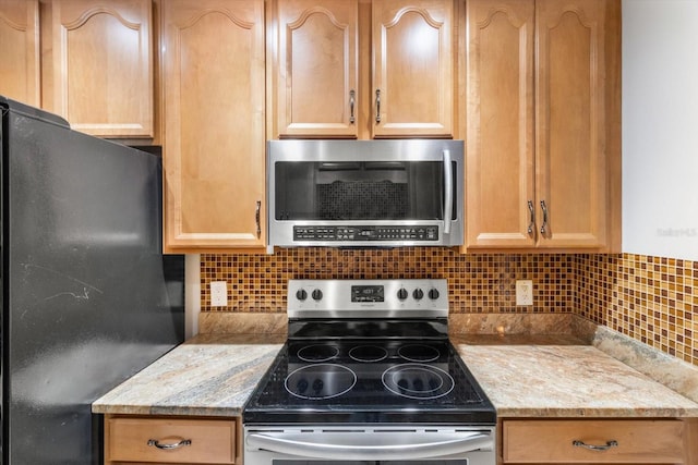 kitchen featuring light stone countertops, light brown cabinets, decorative backsplash, and appliances with stainless steel finishes