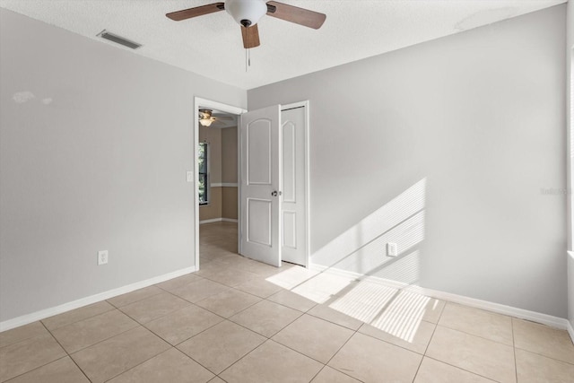 empty room featuring visible vents, tile patterned floors, ceiling fan, and baseboards