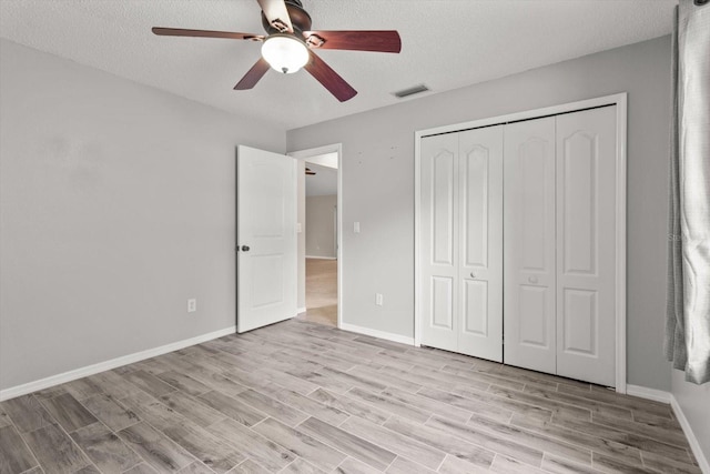 unfurnished bedroom featuring light wood-type flooring, a closet, visible vents, and a textured ceiling