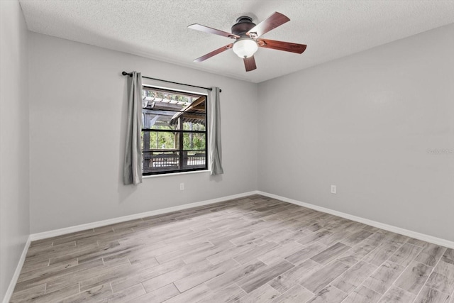 spare room featuring a textured ceiling, light wood-type flooring, baseboards, and ceiling fan