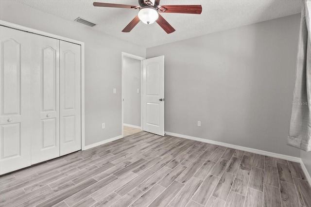 unfurnished bedroom featuring light wood-type flooring, a closet, visible vents, and a textured ceiling