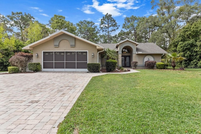 view of front of home featuring a garage, stucco siding, a front lawn, and decorative driveway