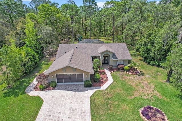 view of front facade with a garage, stucco siding, glass enclosure, a front yard, and driveway