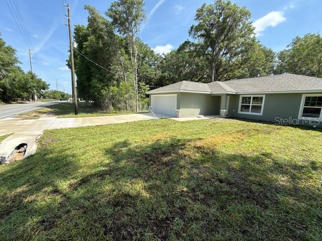 exterior space with an attached garage, stucco siding, driveway, and a front yard