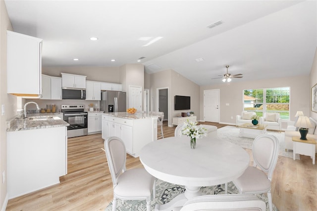 dining space featuring ceiling fan, visible vents, baseboards, lofted ceiling, and light wood-style flooring