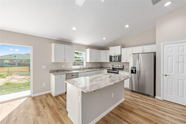 kitchen featuring a sink, light wood finished floors, stainless steel appliances, white cabinetry, and a kitchen island