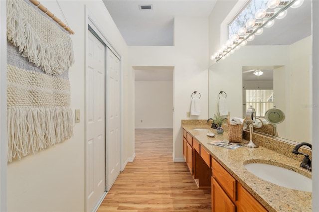 bathroom featuring double vanity, visible vents, a sink, and wood finished floors