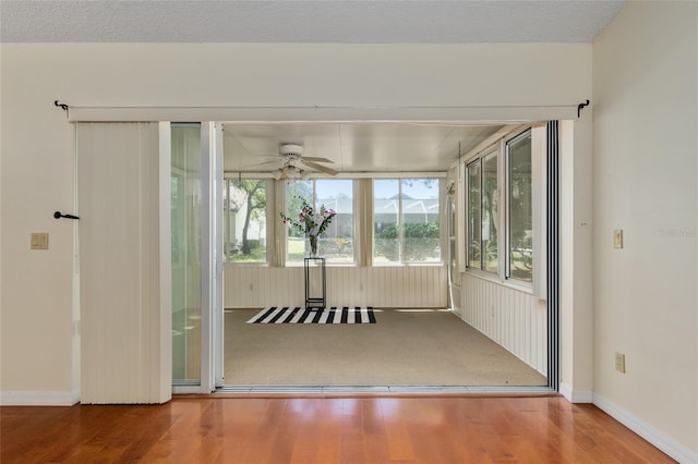 interior space with baseboards, a ceiling fan, and wood finished floors
