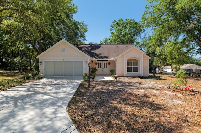 ranch-style home featuring an attached garage, a shingled roof, and concrete driveway