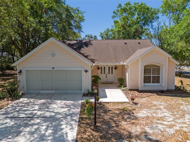 ranch-style house with roof with shingles, an attached garage, and concrete driveway