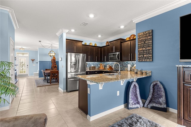 5220 Sunshine Dr, Wildwood, FL 34785 - kitchen with dark brown cabinetry, a peninsula, appliances with stainless steel finishes, light stone counters, and a sink