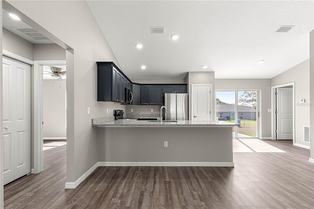 kitchen featuring light stone countertops, visible vents, wood finished floors, and appliances with stainless steel finishes