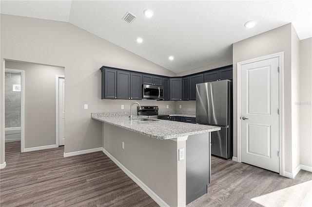 kitchen with visible vents, a sink, appliances with stainless steel finishes, a peninsula, and vaulted ceiling
