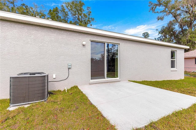 rear view of property with a yard, a patio, central air condition unit, and stucco siding