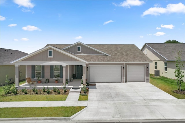 craftsman house featuring concrete driveway, a front yard, central AC unit, a garage, and a shingled roof