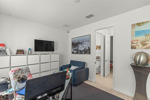 office area featuring a textured ceiling, baseboards, and visible vents