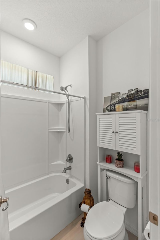 full bathroom featuring toilet, bathtub / shower combination, wood finished floors, and a textured ceiling