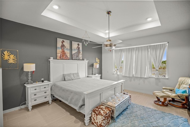 bedroom featuring recessed lighting, a tray ceiling, baseboards, and a skylight