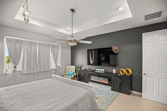 bedroom featuring visible vents, recessed lighting, a raised ceiling, light wood finished floors, and baseboards