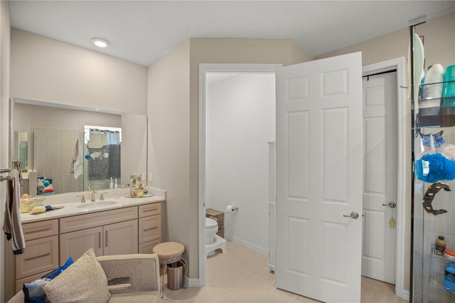 full bath with toilet, tiled shower, vanity, and baseboards