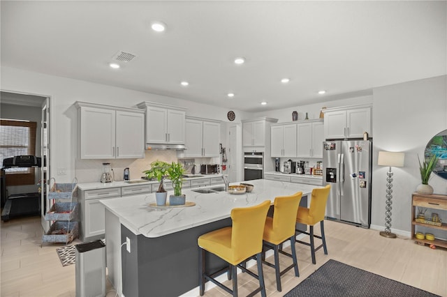 kitchen featuring visible vents, recessed lighting, a center island with sink, and stainless steel appliances