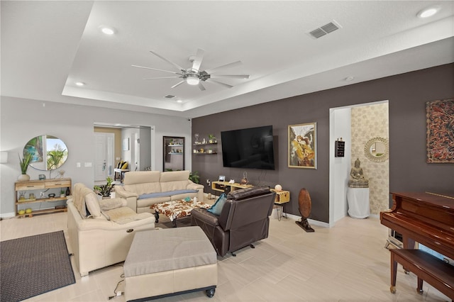 living area with baseboards, recessed lighting, visible vents, a tray ceiling, and ceiling fan