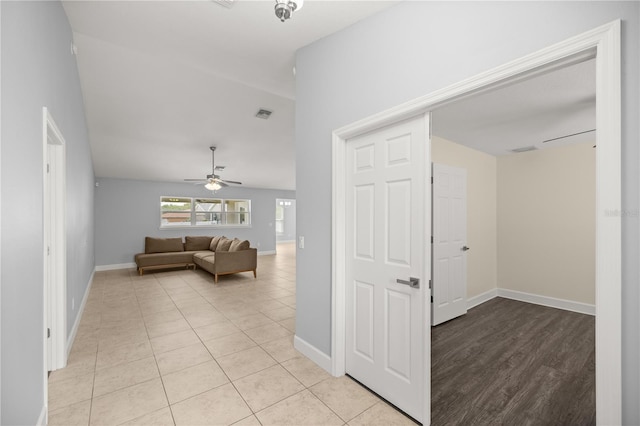 hall featuring light tile patterned flooring, baseboards, lofted ceiling, and visible vents