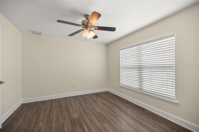 spare room with visible vents, baseboards, a ceiling fan, and dark wood-style floors