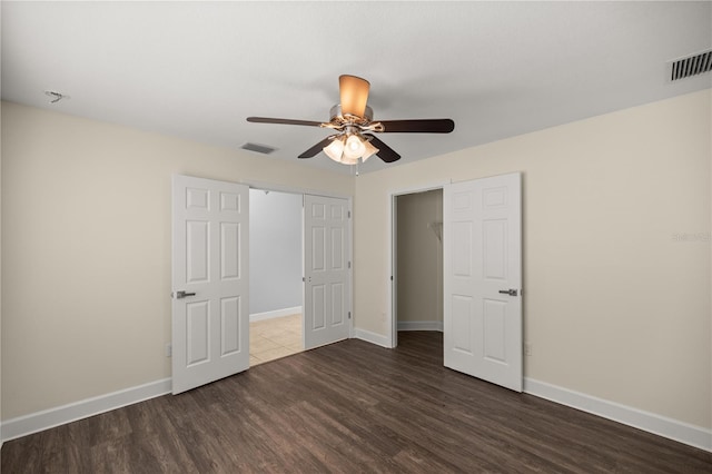 unfurnished bedroom featuring wood finished floors, baseboards, a closet, and visible vents