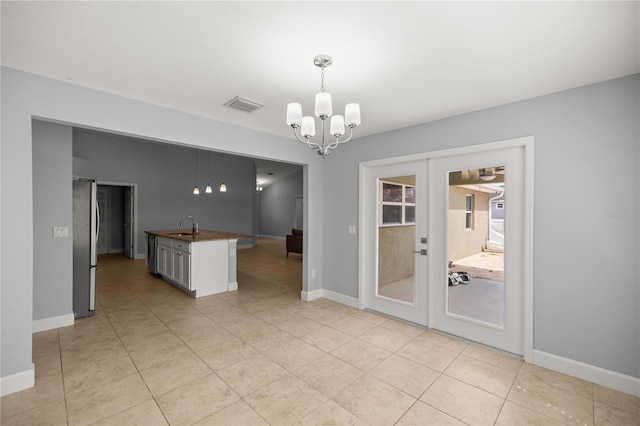unfurnished dining area with visible vents, an inviting chandelier, a sink, french doors, and light tile patterned flooring