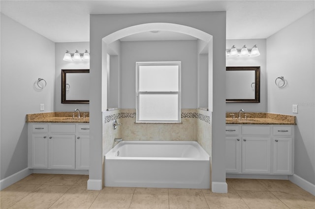 full bath featuring two vanities, a sink, and a garden tub