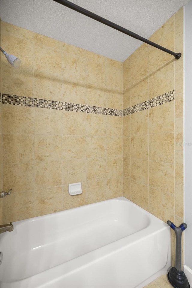 bathroom featuring a textured ceiling and tub / shower combination