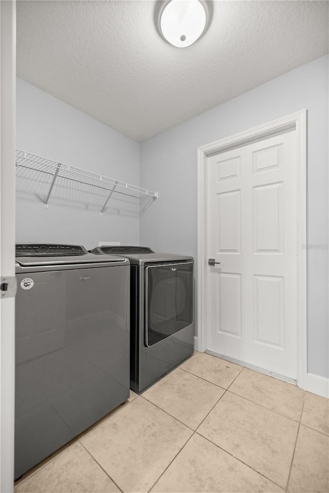 laundry area with light tile patterned floors, baseboards, laundry area, a textured ceiling, and independent washer and dryer