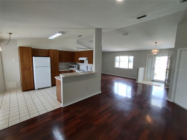 10315 SW 62nd Terrace Rd, Ocala, FL 34476 - kitchen featuring freestanding refrigerator, stainless steel microwave, lofted ceiling, light wood-type flooring, and a peninsula