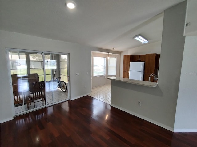 10315 SW 62nd Terrace Rd, Ocala, FL 34476 - kitchen with freestanding refrigerator, wood finished floors, baseboards, lofted ceiling, and hanging light fixtures