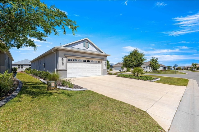 view of front of home featuring a residential view, concrete driveway, a front yard, and stucco siding
