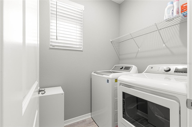 laundry area featuring light wood-style flooring, baseboards, washer and clothes dryer, and laundry area