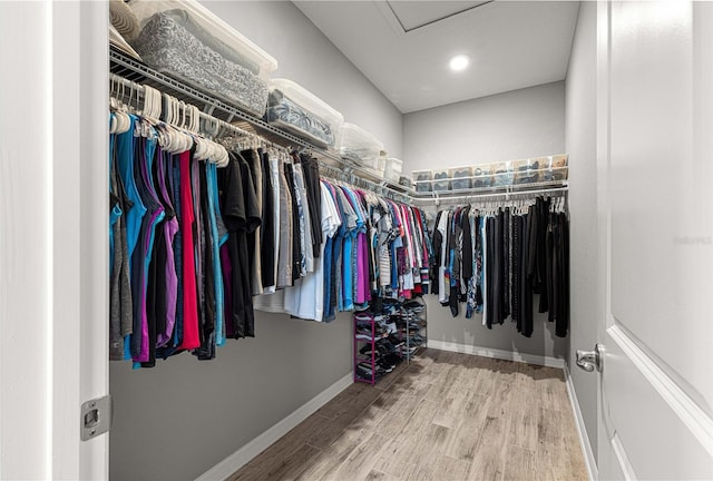 walk in closet with attic access and wood finished floors