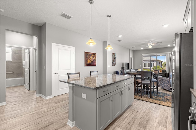 kitchen with freestanding refrigerator, light wood-type flooring, visible vents, and gray cabinetry