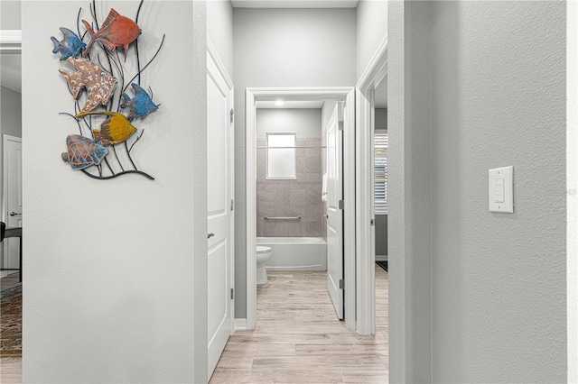 hallway featuring light wood-style floors and a textured wall