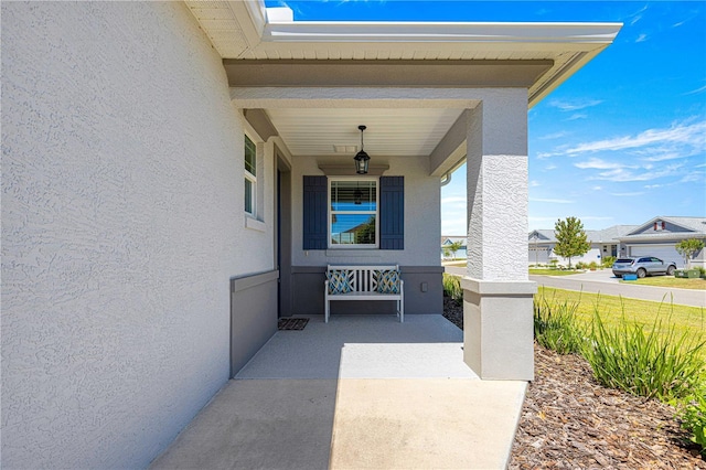 property entrance featuring stucco siding, a residential view, and covered porch