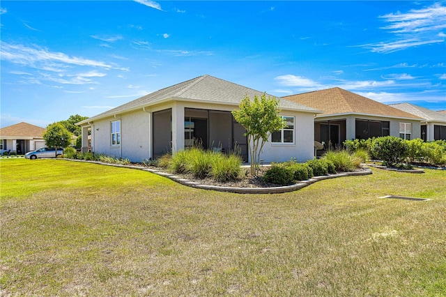 back of property featuring stucco siding, a sunroom, and a yard