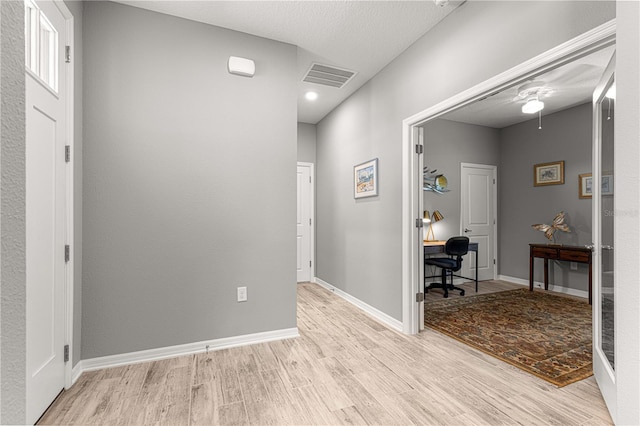 corridor featuring baseboards, visible vents, and light wood-type flooring