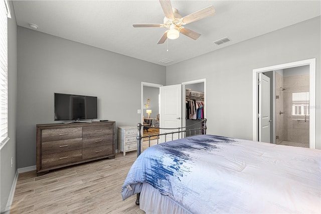 bedroom with visible vents, a walk in closet, light wood-type flooring, baseboards, and ceiling fan