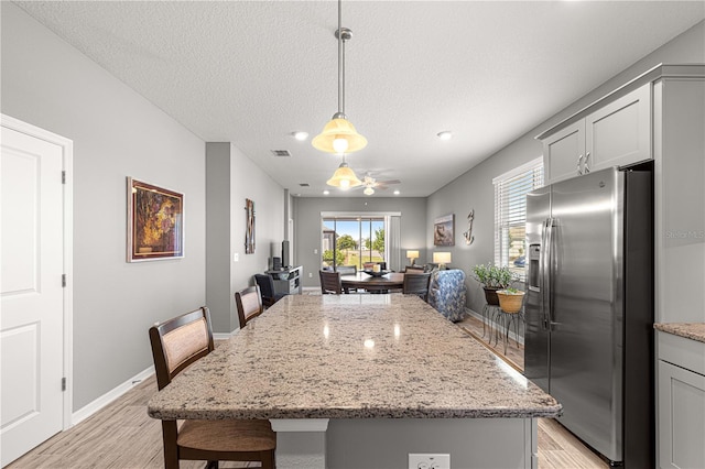 dining space with baseboards, a ceiling fan, visible vents, and light wood-style flooring